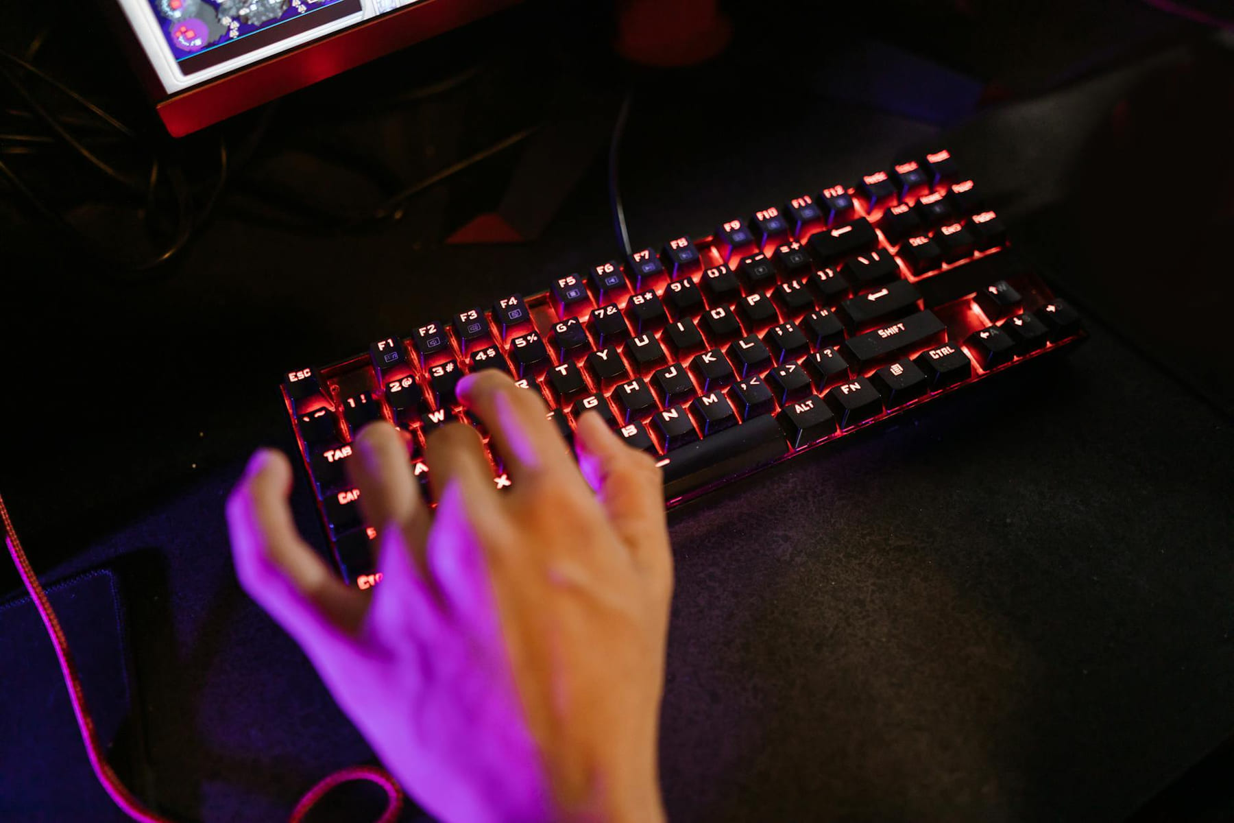 A hand engaging with a glowing mechanical gaming keyboard in a dark setting. on Frame Rate Vault