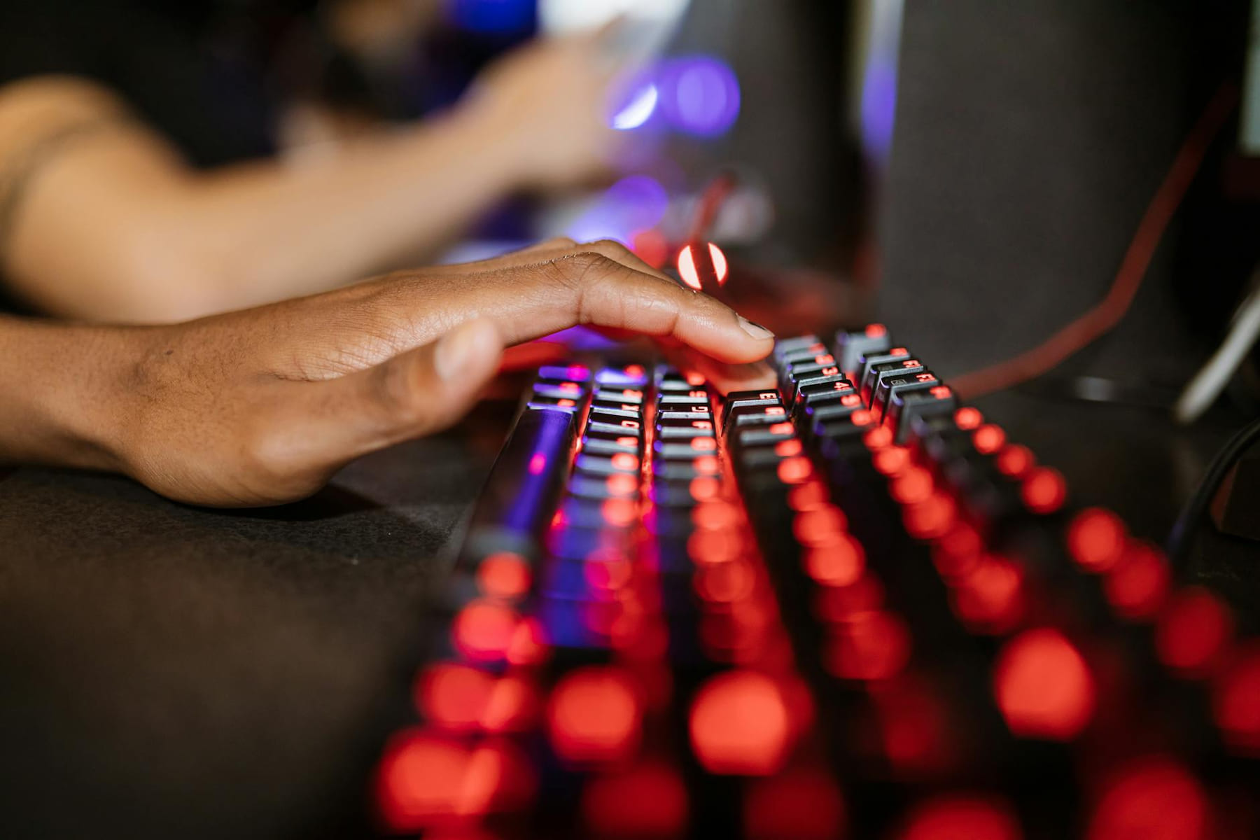 Close-up of a hand on a vibrant RGB-lit gaming keyboard during gameplay. on Frame Rate Vault