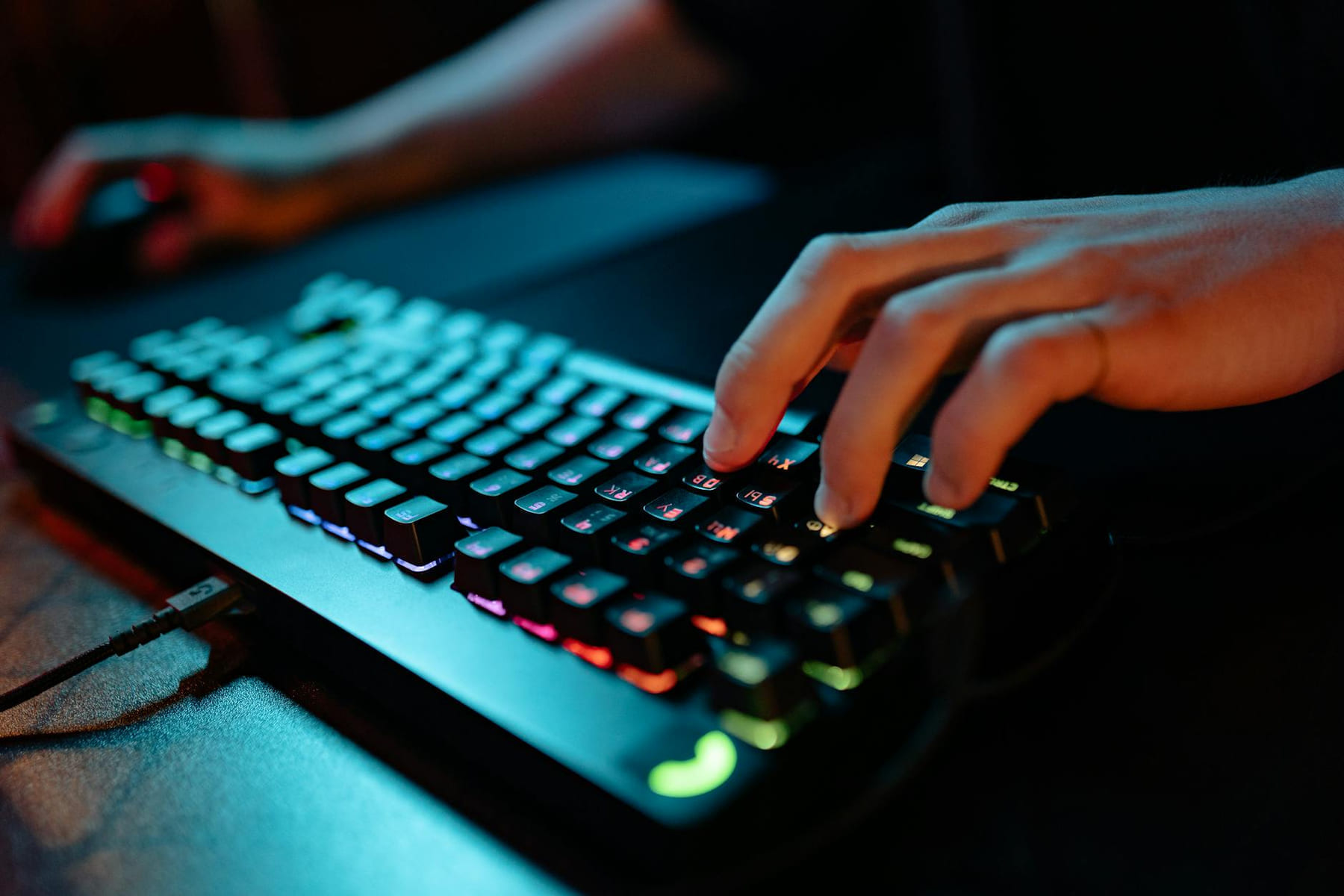 Hands typing on a glowing RGB keyboard during a gaming session indoors. on Frame Rate Vault