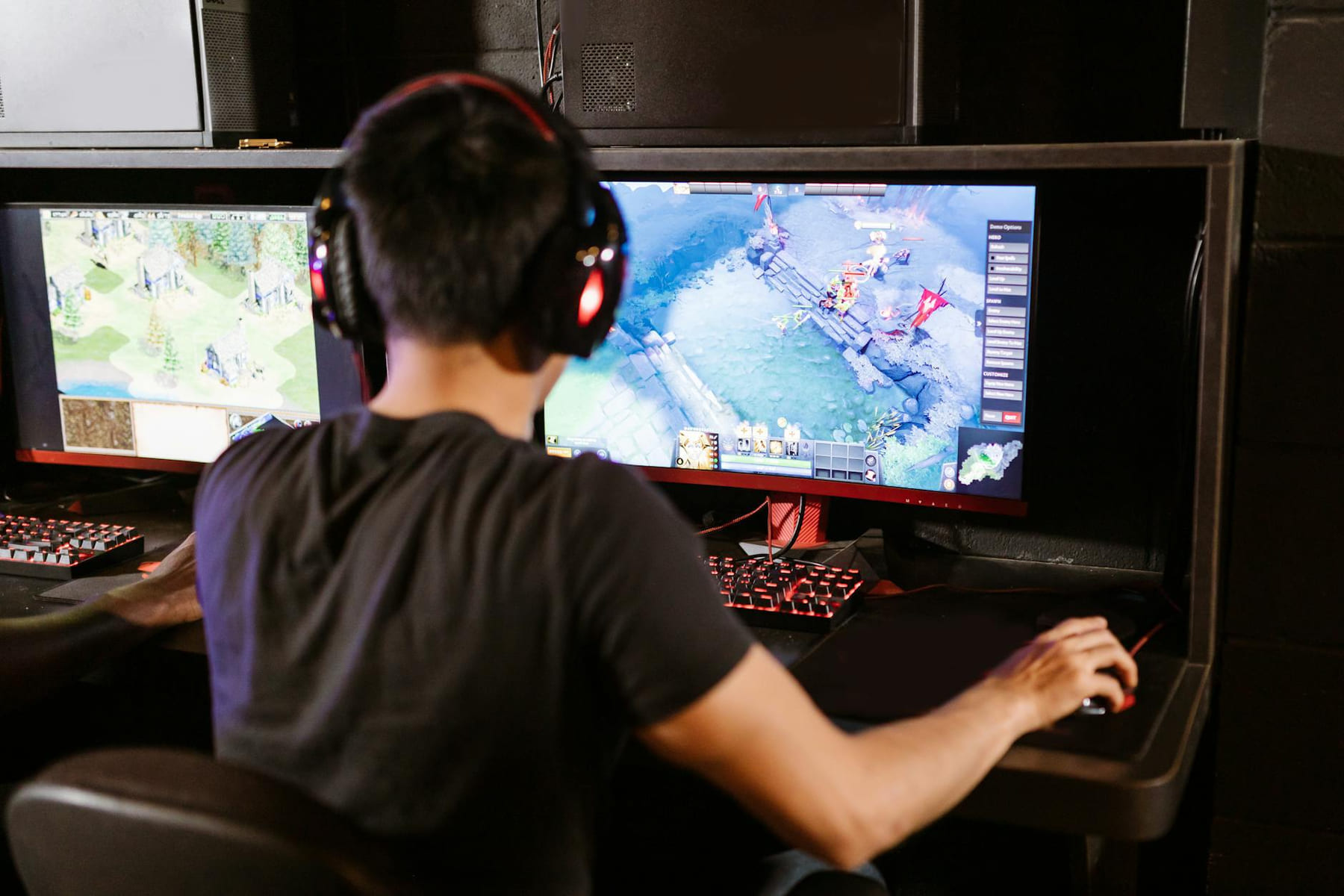 Adult male gamer immersed in PC gaming on dual monitors with headphones indoors. on Frame Rate Vault