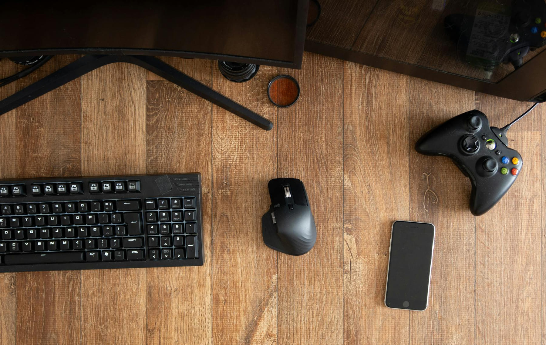 Top view of black gamepad with mouse and keyboard on wooden desk with monitor in apartment in daytime on Frame Rate Vault
